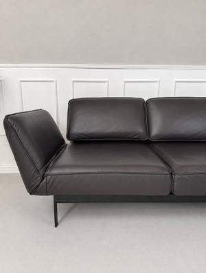 Gebrauchtes schwarz-braunes Rolf Benz Mera Designer Leder Sofa vor einer Wand, stilvoll und modern eingerichtet.