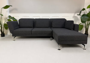 Gebrauchtes graues Brühl Moule Designer Stoff Sofa vor einer Wand, stilvoll und modern eingerichtet.
