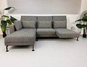 Gebrauchtes graues Brühl Moule Designer Stoff Sofa vor einer Wand, stilvoll und modern eingerichtet.