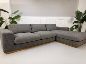 Gebrauchtes graues Bolia Sepia Designer Stoff Sofa vor einer Wand, stilvoll und modern eingerichtet.