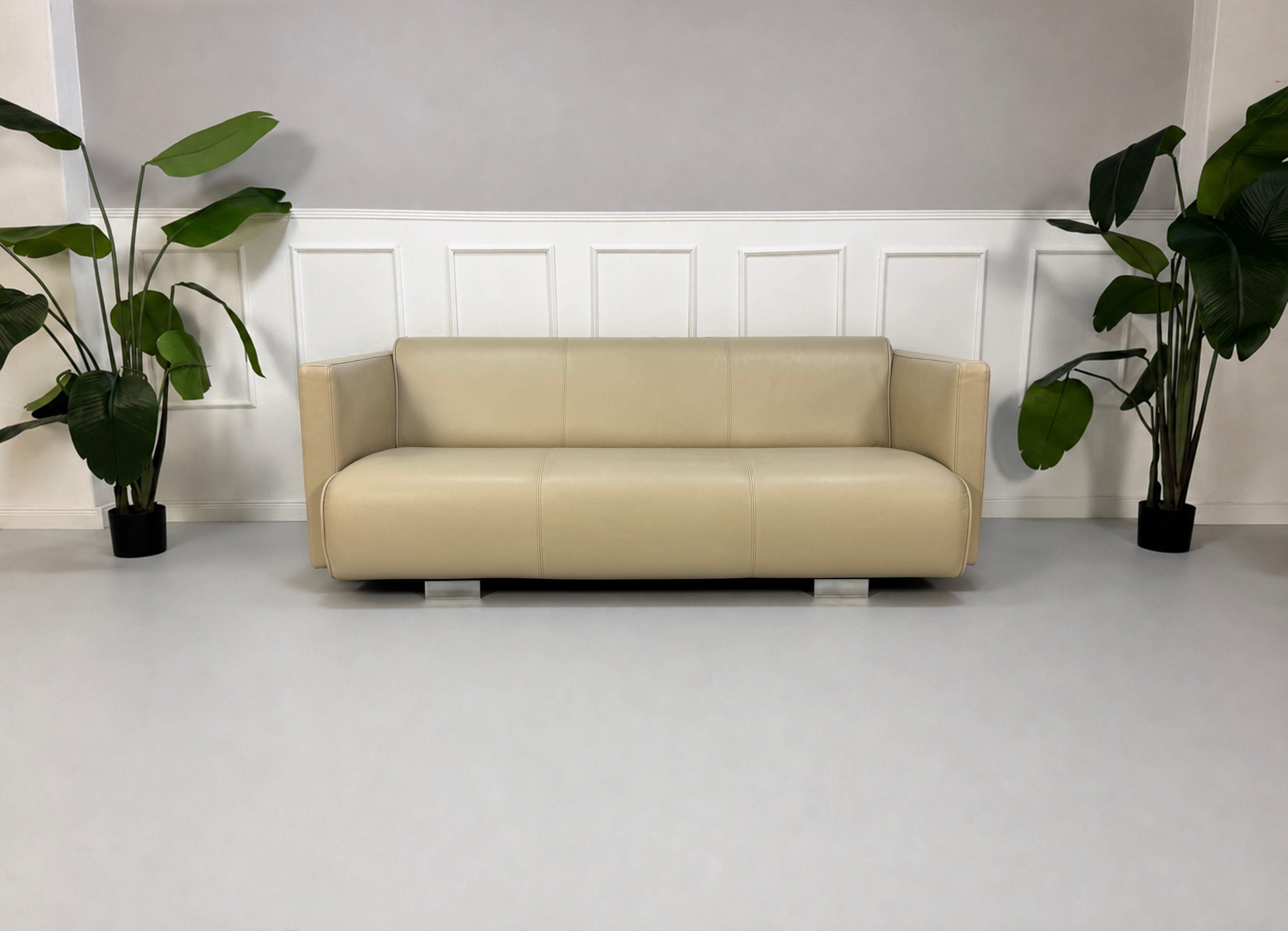 Gebrauchtes beiges Rolf Benz 6300 Designer Leder Sofa vor einer Wand, stilvoll und modern eingerichtet.