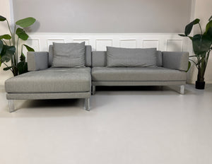 Gebrauchtes graues Rolf Benz Sento Designer Stoff Sofa vor einer Wand, stilvoll und modern eingerichtet.