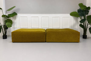 Gebrauchte gelbe Bolia Cosima Designer Stoff Hocker vor einer Wand, stilvoll und modern eingerichtet.