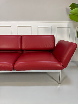Gebrauchtes rotes Brühl Roro Medium Designer Leder Sofa vor einer Wand, stilvoll und modern eingerichtet.