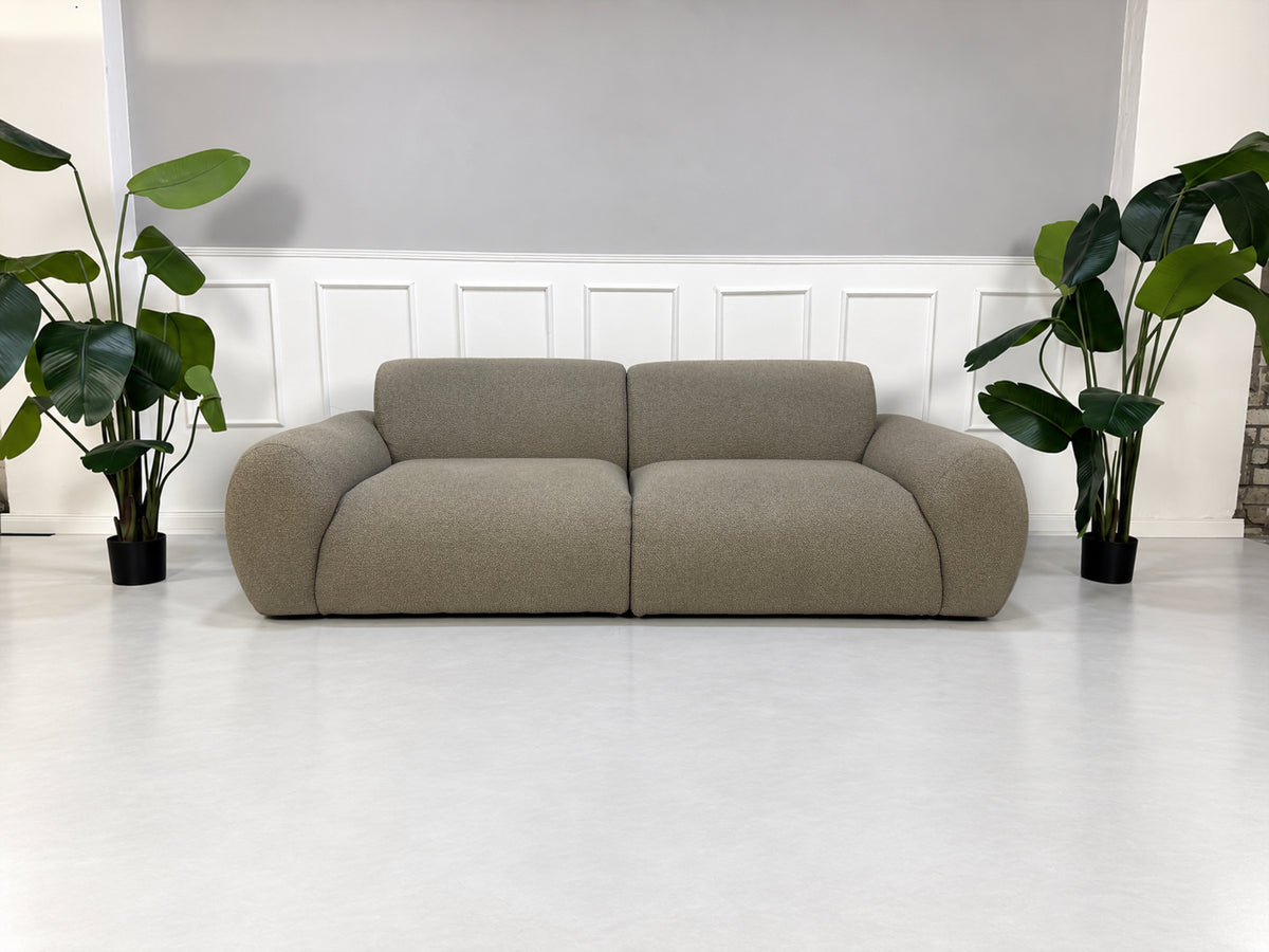 Gebrauchtes grau-beiges Bolia Núvol Designer Stoff Sofa vor einer Wand, stilvoll und modern eingerichtet.