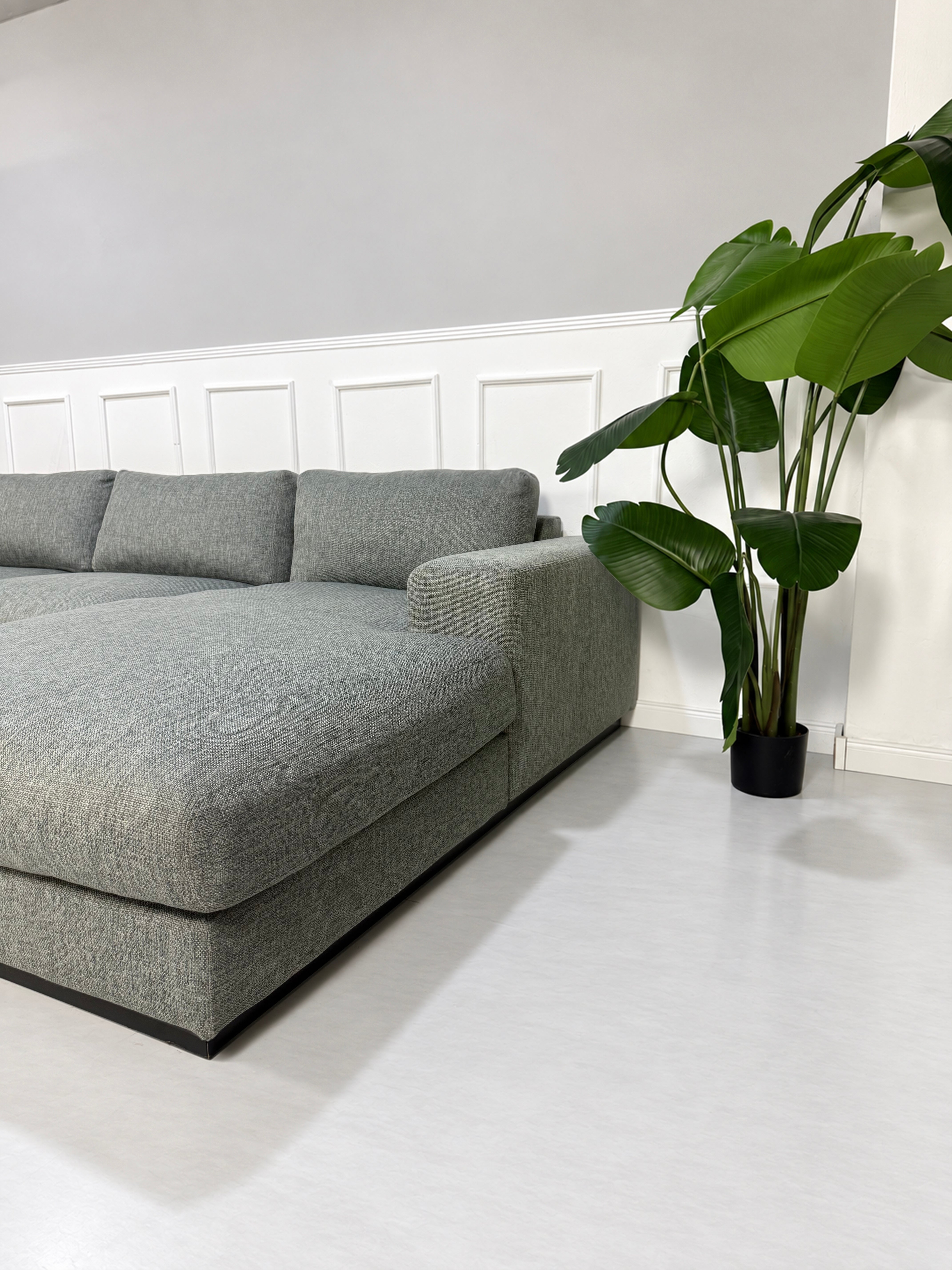 Gebrauchtes graues Bolia Sepia Designer Stoff Ecksofa vor einer Wand, stilvoll und modern eingerichtet.