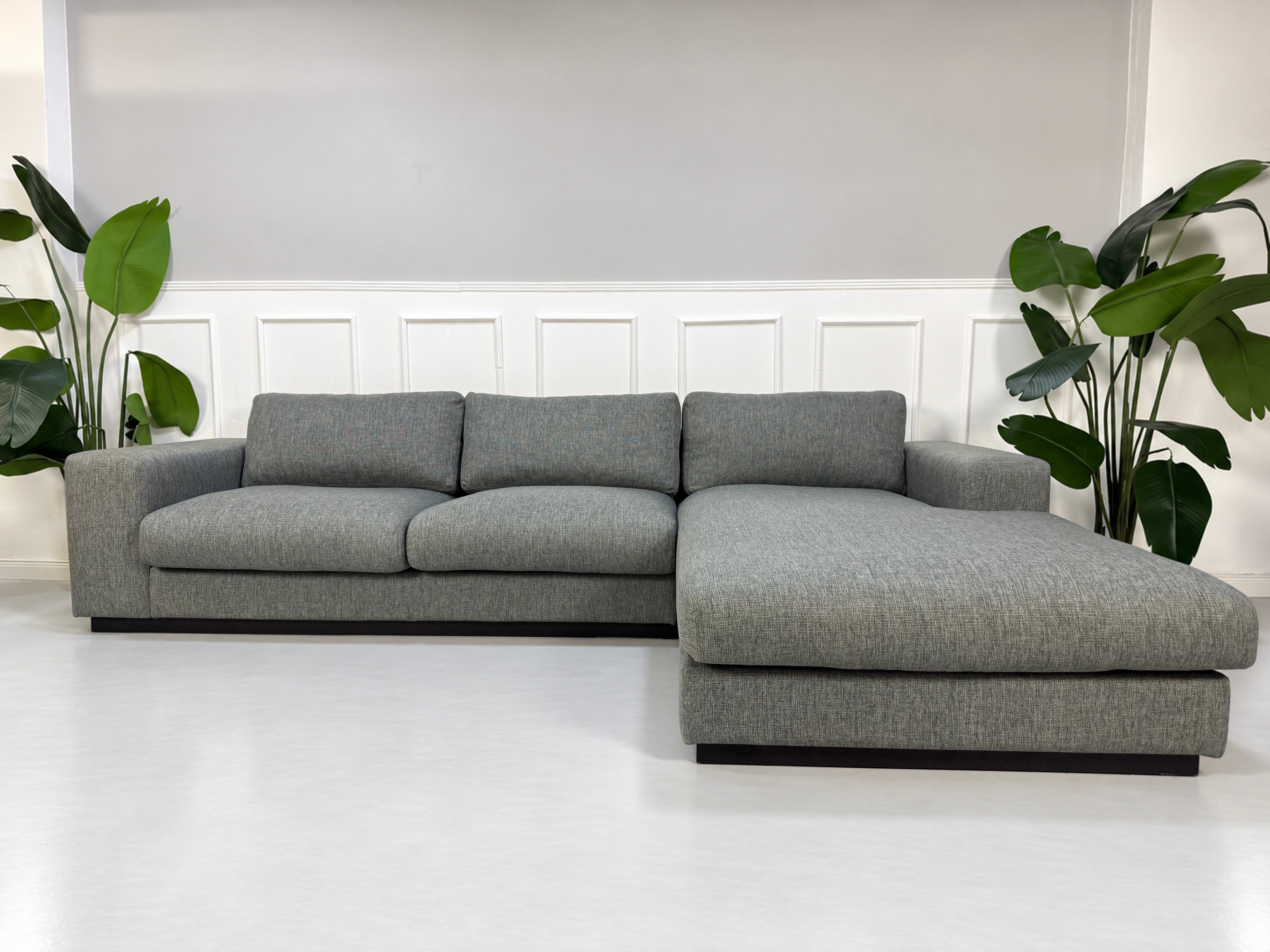 Gebrauchtes graues Bolia Sepia Designer Stoff Ecksofa vor einer Wand, stilvoll und modern eingerichtet.
