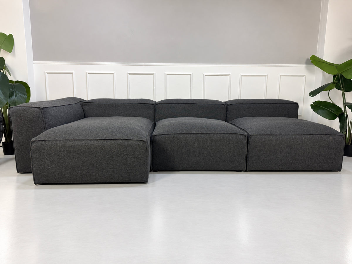 Gebrauchtes graues Bolia Cosima Designer Stoff Sofa vor einer Wand, stilvoll und modern eingerichtet.