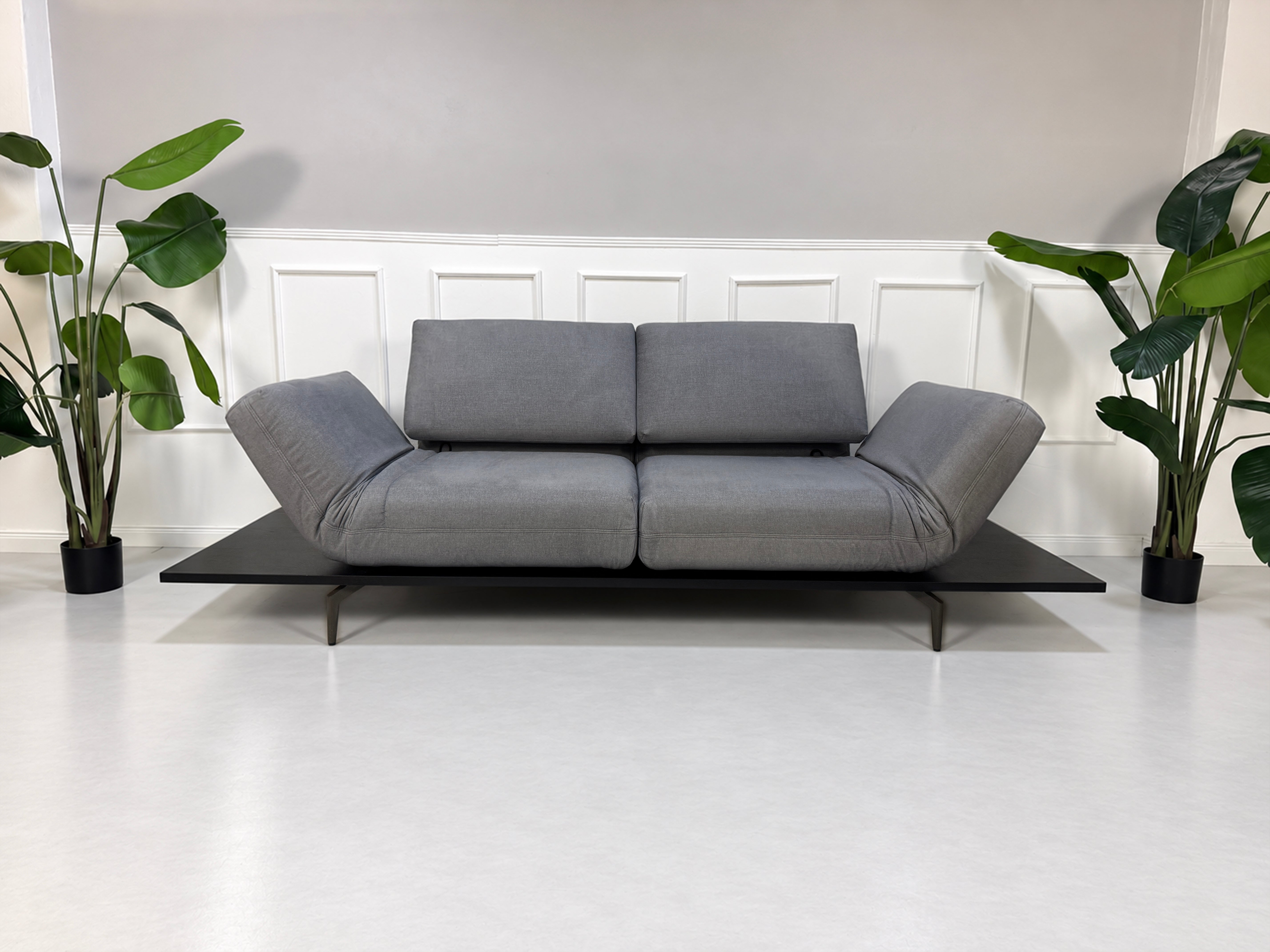 Gebrauchtes grau-blaues Rolf Benz Aura Designer Stoff Sofa vor einer Wand, stilvoll und modern eingerichtet.