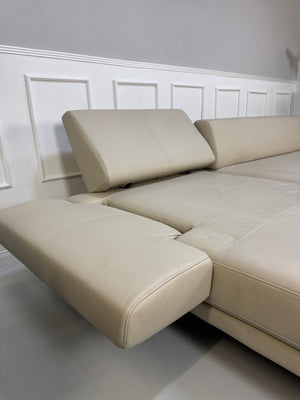 Gebrauchtes beiges Rolf Benz Sento 344 Designer Leder Ecksofa mit Hockerbank vor einer Wand, stilvoll und modern eingerichtet.