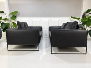 Gebrauchtes schwarzes COR Mell Designer Leder Sofa vor einer Wand, stilvoll und modern eingerichtet.