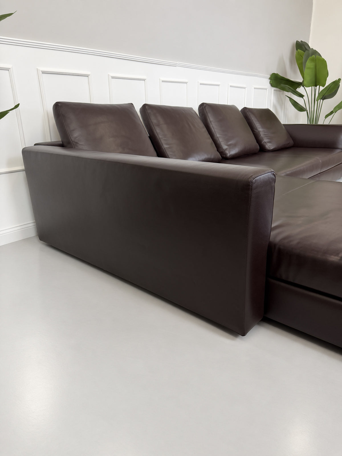 Gebrauchtes braunes Minotti Kline Designer Leder Ecksofa mit Hocker vor einer Wand, stilvoll und modern eingerichtet.