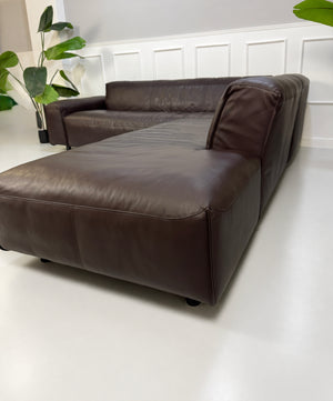 Gebrauchtes braunes Rolf Benz Mio Designer Leder Ecksofa vor einer Wand, stilvoll und modern eingerichtet.