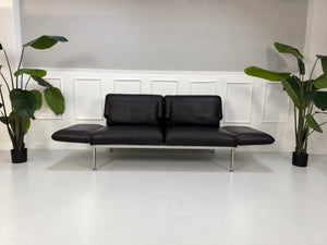 Gebrauchtes schwarzes Brühl Roro Medium Designer Leder Sofa vor einer Wand, stilvoll und modern eingerichtet.