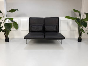 Gebrauchtes schwarzes Brühl Roro Medium Designer Leder Sofa vor einer Wand, stilvoll und modern eingerichtet.