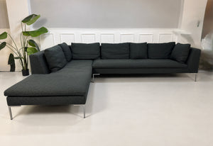 Gebrauchtes graues B&B Italia Charles Designer Stoff Ecksofa vor einer Wand, stilvoll und modern eingerichtet.