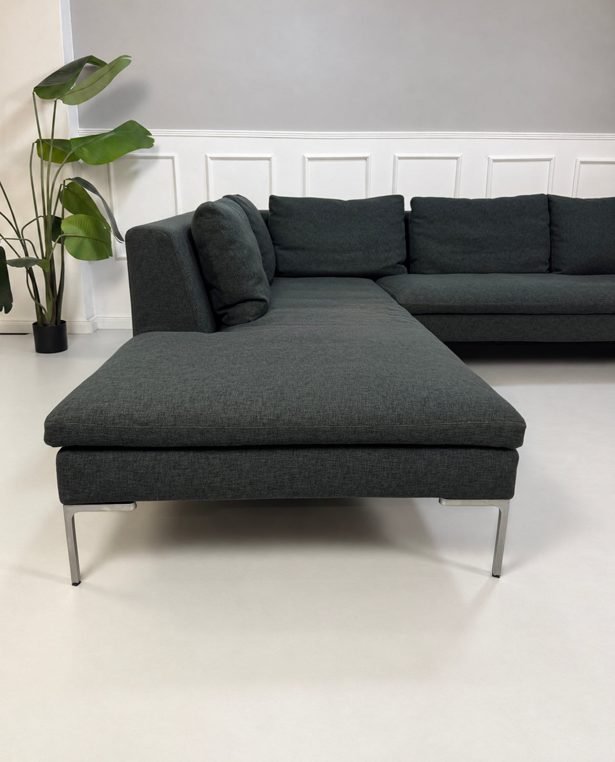 Gebrauchtes graues B&B Italia Charles Designer Stoff Ecksofa vor einer Wand, stilvoll und modern eingerichtet.