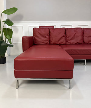 Gebrauchtes rotes Brühl Fourtwo Designer Leder Ecksofa vor einer Wand, stilvoll und modern eingerichtet.