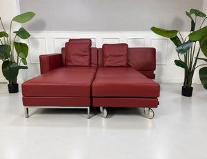Gebrauchtes rotes Brühl Fourtwo Designer Leder Ecksofa vor einer Wand, stilvoll und modern eingerichtet.