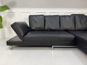Gebrauchtes schwarzes Brühl Fourtwo Designer Leder Ecksofa vor einer Wand, stilvoll und modern eingerichtet.