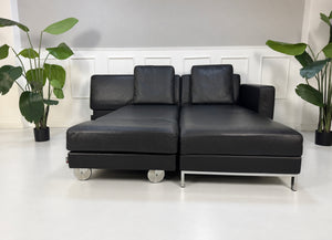 Gebrauchtes schwarzes Brühl Fourtwo Designer Leder Ecksofa vor einer Wand, stilvoll und modern eingerichtet.