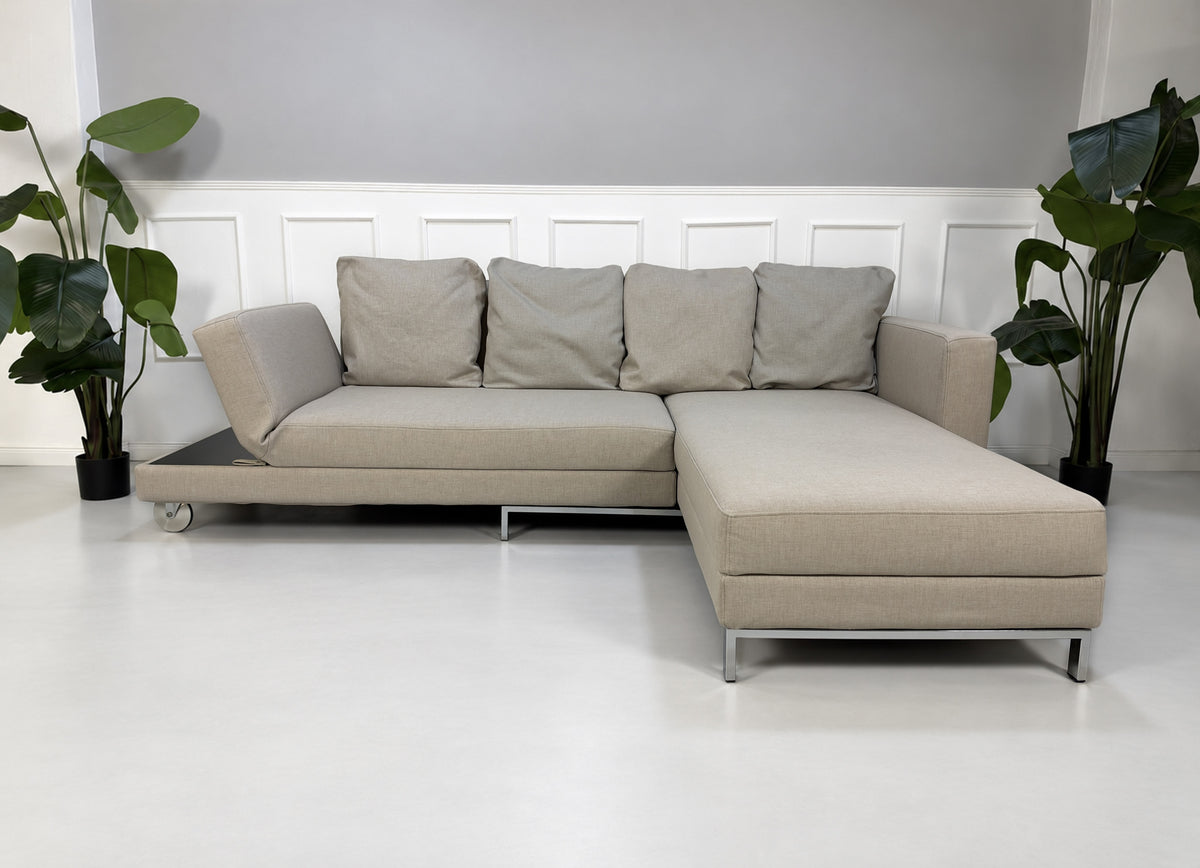 Gebrauchtes beiges Brühl Fourtwo Designer Stoff Ecksofa vor einer Wand, stilvoll und modern eingerichtet.