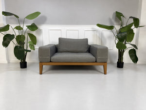 Gebrauchtes graues Flexform Lifewood Designer Stoff Sofa mit Love Chair vor einer Wand, stilvoll und modern eingerichtet.