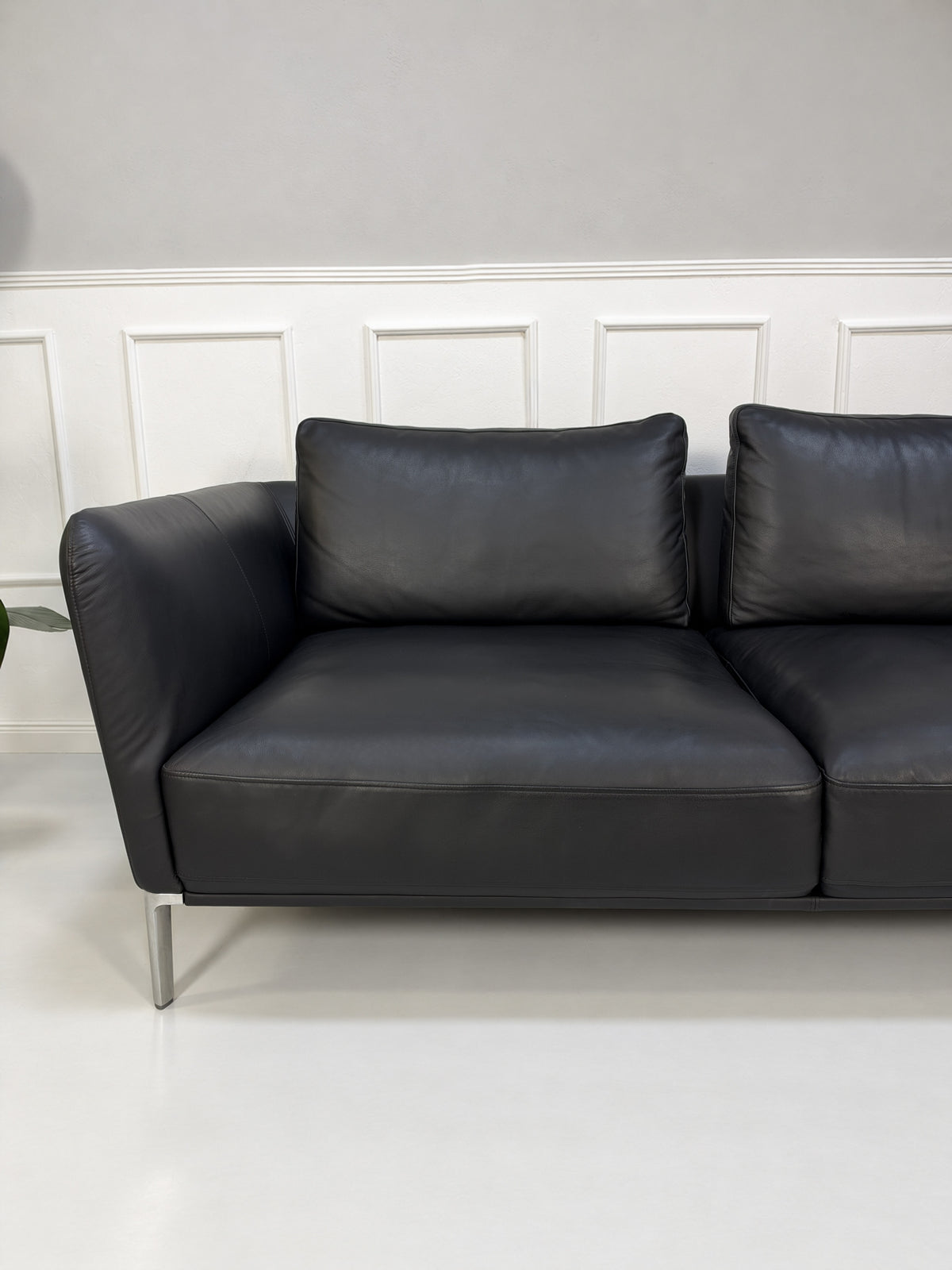 Gebrauchtes schwarzes Rolf Benz Scala Designer Leder Sofa vor einer Wand, stilvoll und modern eingerichtet.