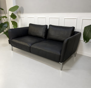 Gebrauchtes schwarzes Rolf Benz Scala Designer Leder Sofa vor einer Wand, stilvoll und modern eingerichtet.