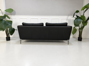 Gebrauchtes schwarzes Rolf Benz Scala Designer Leder Sofa vor einer Wand, stilvoll und modern eingerichtet.