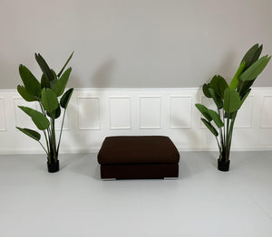 Gebrauchter brauner BoConcept Stoff Hocker vor einer Wand, stilvoll und modern eingerichtet.