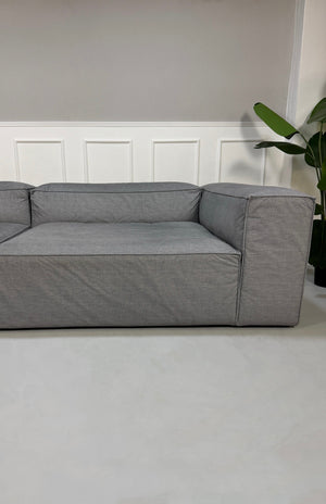 Gebrauchtes graues Bolia Cosima Designer Stoff Sofa vor einer Wand, stilvoll und modern eingerichtet.