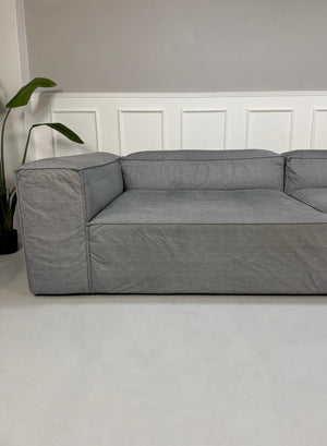 Gebrauchtes graues Bolia Cosima Designer Stoff Sofa vor einer Wand, stilvoll und modern eingerichtet.