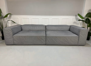 Gebrauchtes graues Bolia Cosima Designer Stoff Sofa vor einer Wand, stilvoll und modern eingerichtet.