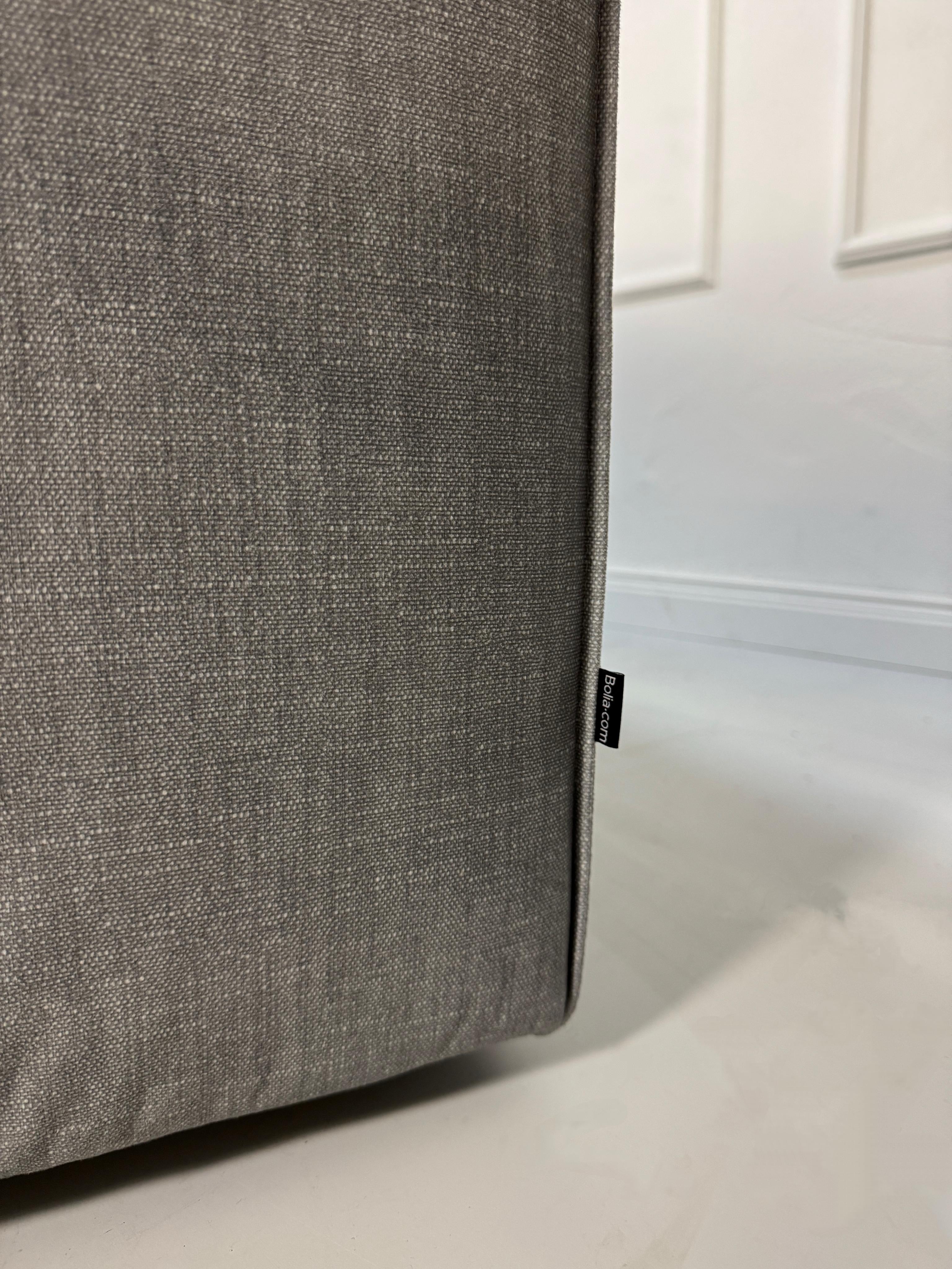 Gebrauchtes graues Bolia Cosima Designer Stoff Sofa vor einer Wand, stilvoll und modern eingerichtet.
