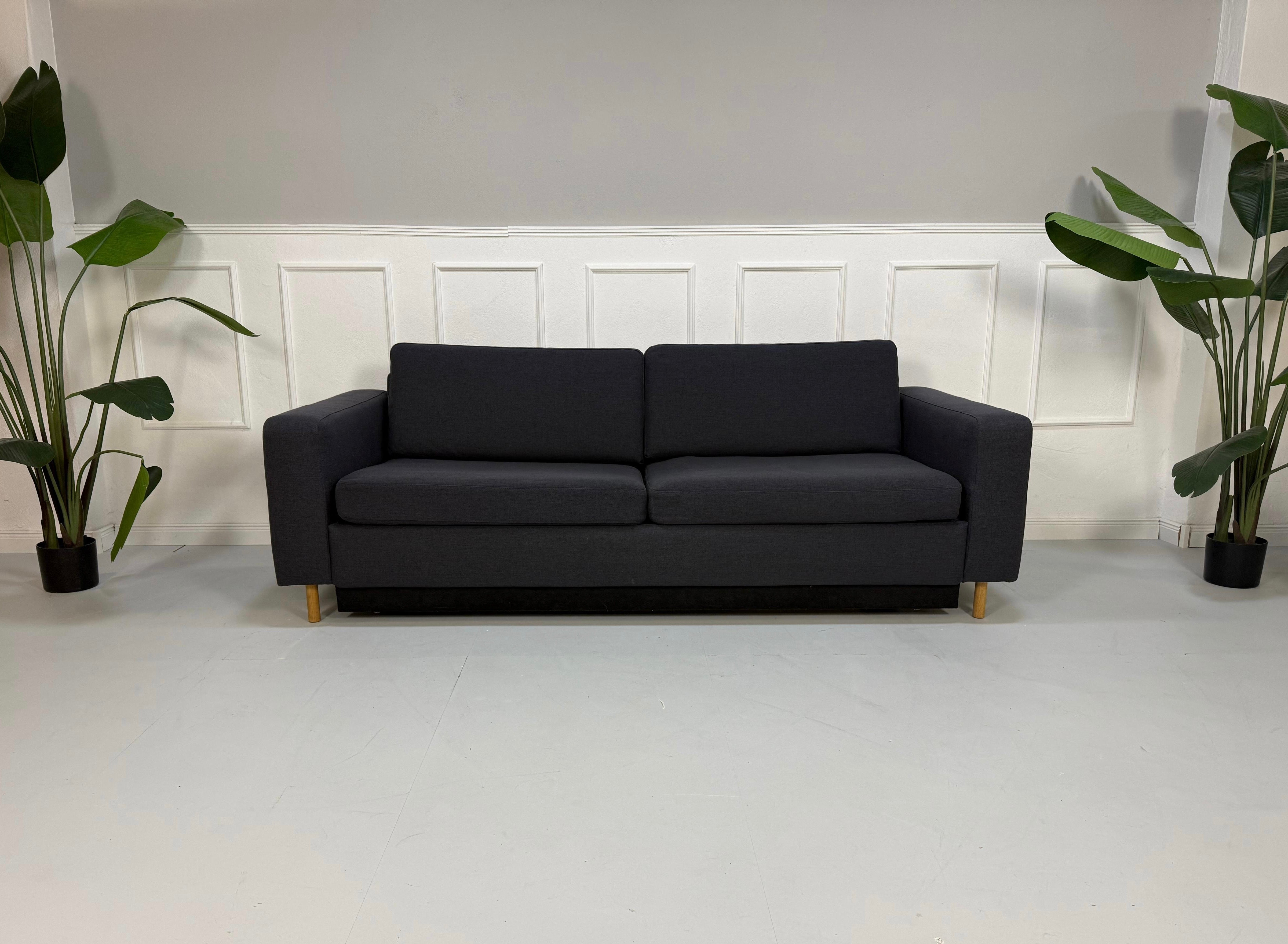 Gebrauchtes blaues Bolia Scandinavia Designer Stoff Sofa vor einer Wand, stilvoll und modern eingerichtet.