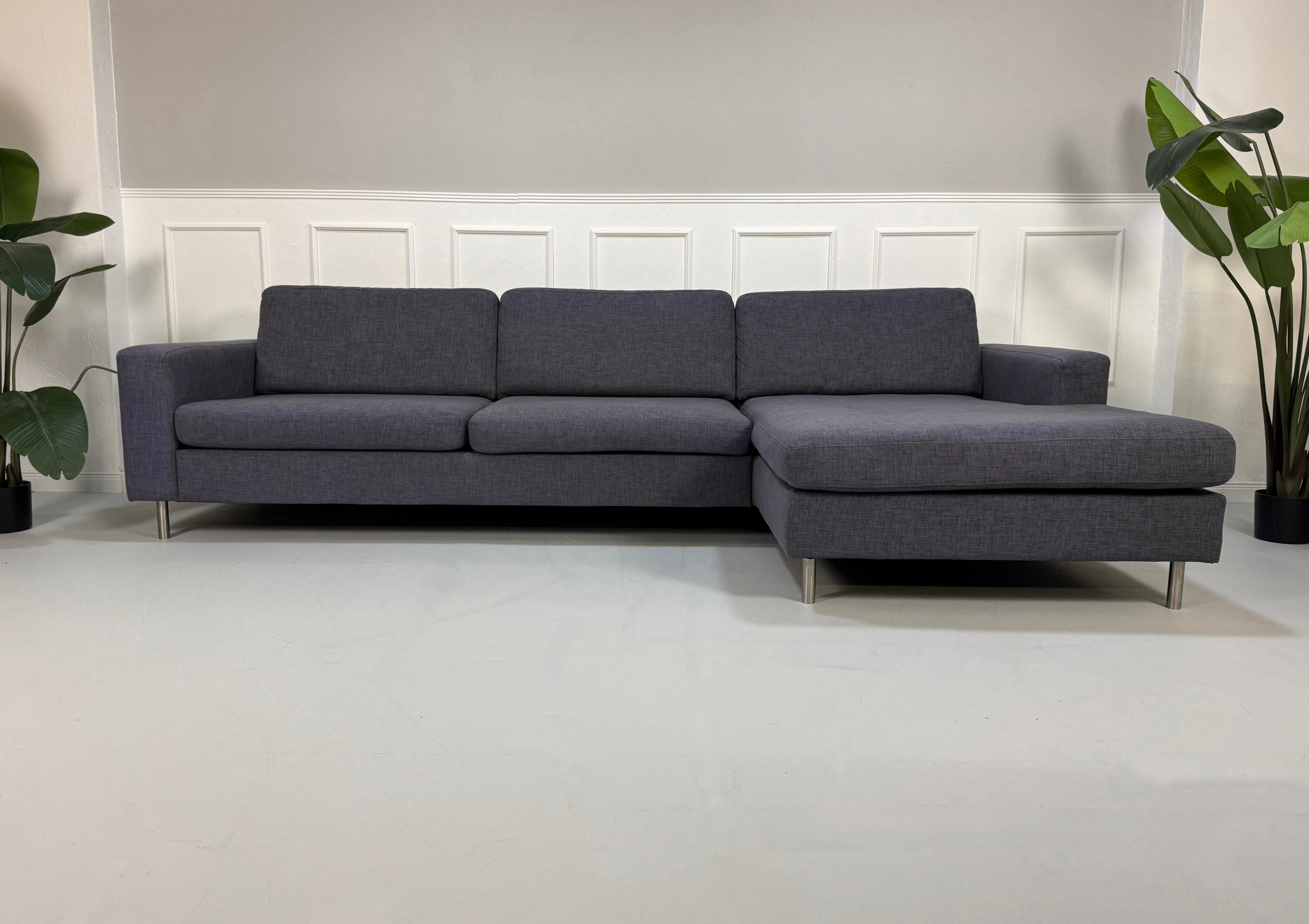 Gebrauchtes lila Bolia Scandinavia Designer Stoff Sofa vor einer Wand, stilvoll und modern eingerichtet.
