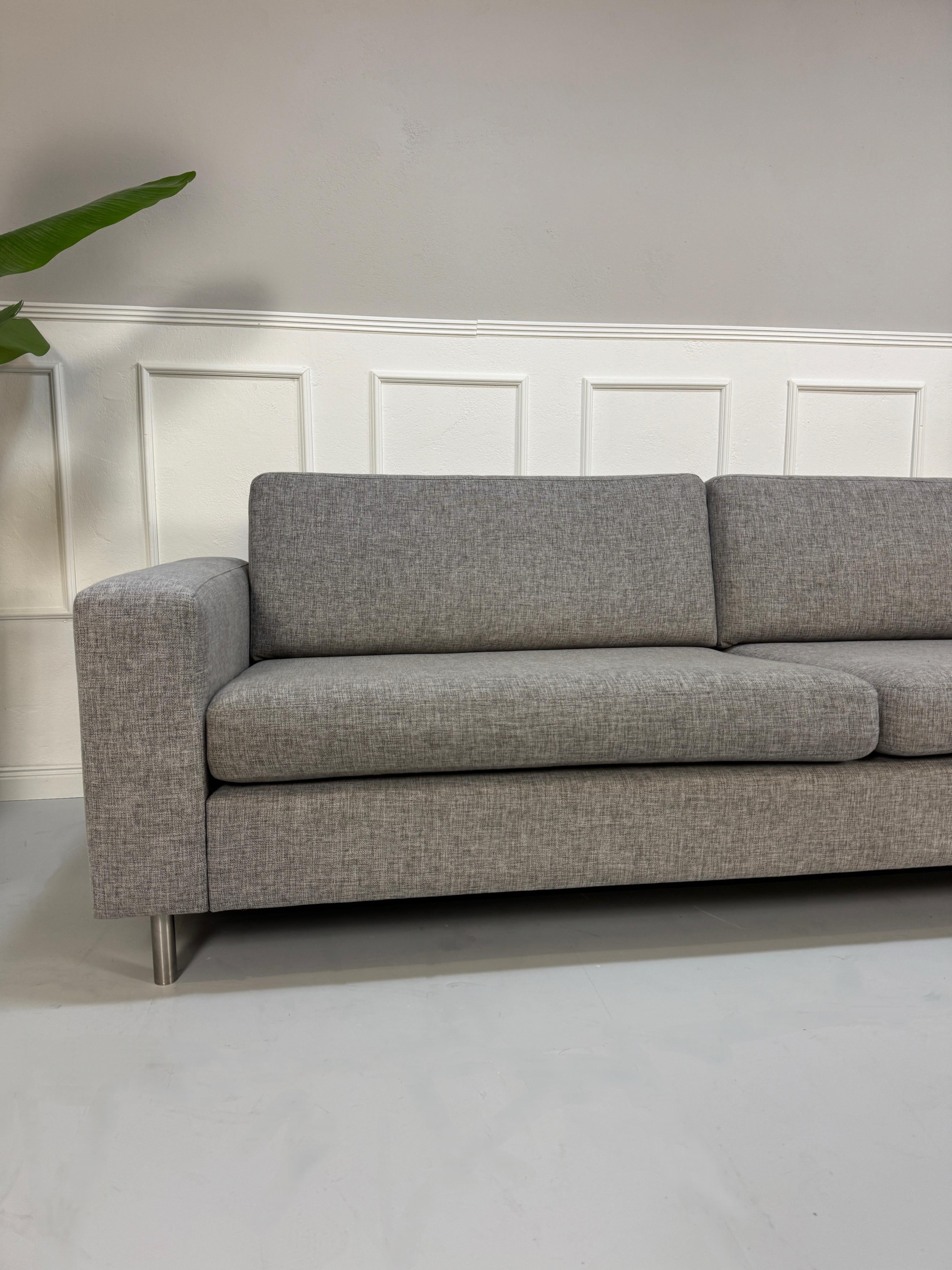Gebrauchtes graues Bolia Scandinavia Designer Stoff Sofa mit Metallfüßen vor einer Wand, stilvoll und modern eingerichtet.