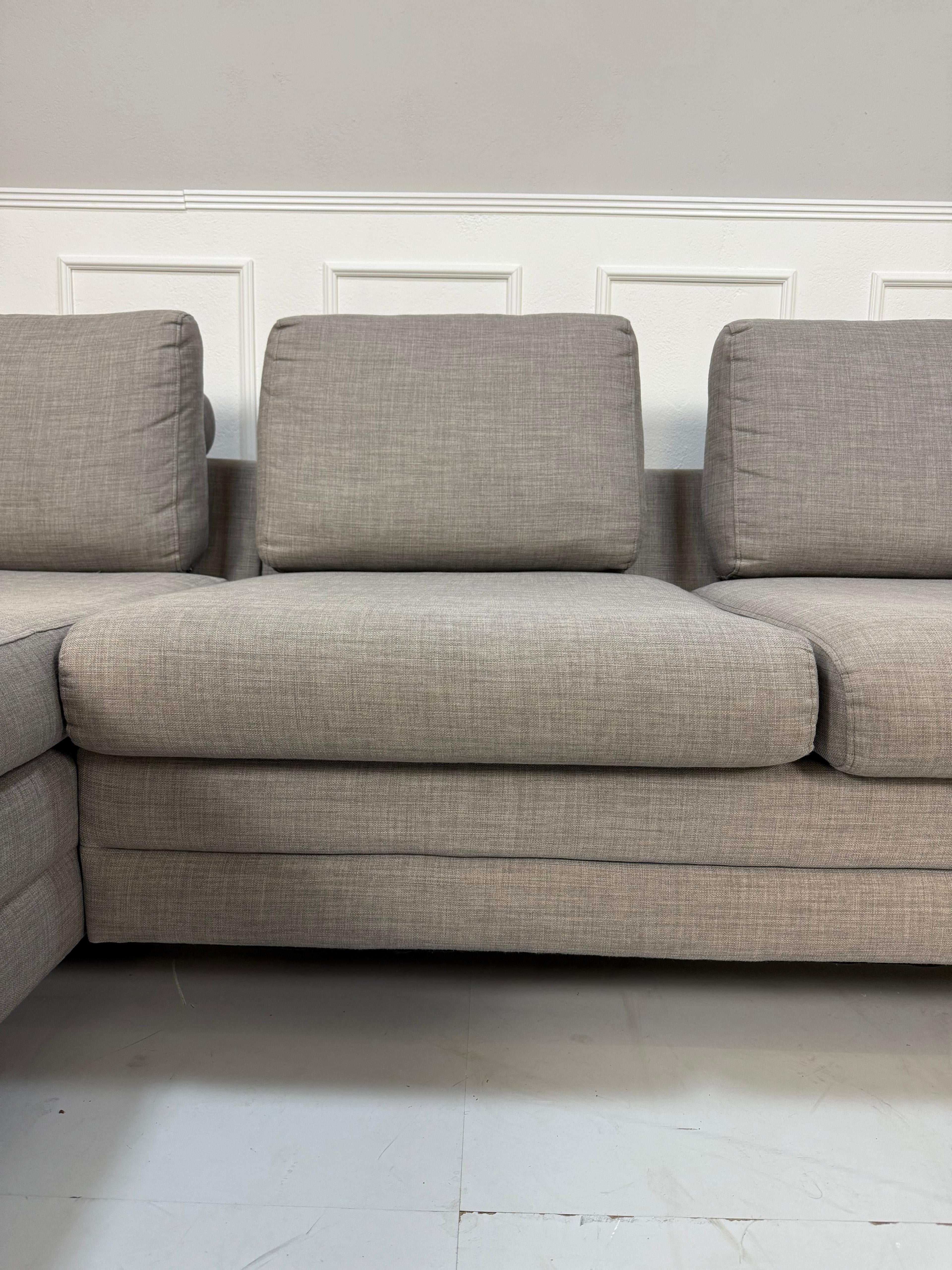 Gebrauchtes graues Bolia Designer Stoff Sofa vor einer Wand, stilvoll und modern eingerichtet.