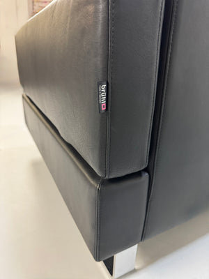 Gebrauchtes schwarzes Ledersofa Brühl Modell Alba vor einer modernen Wand
