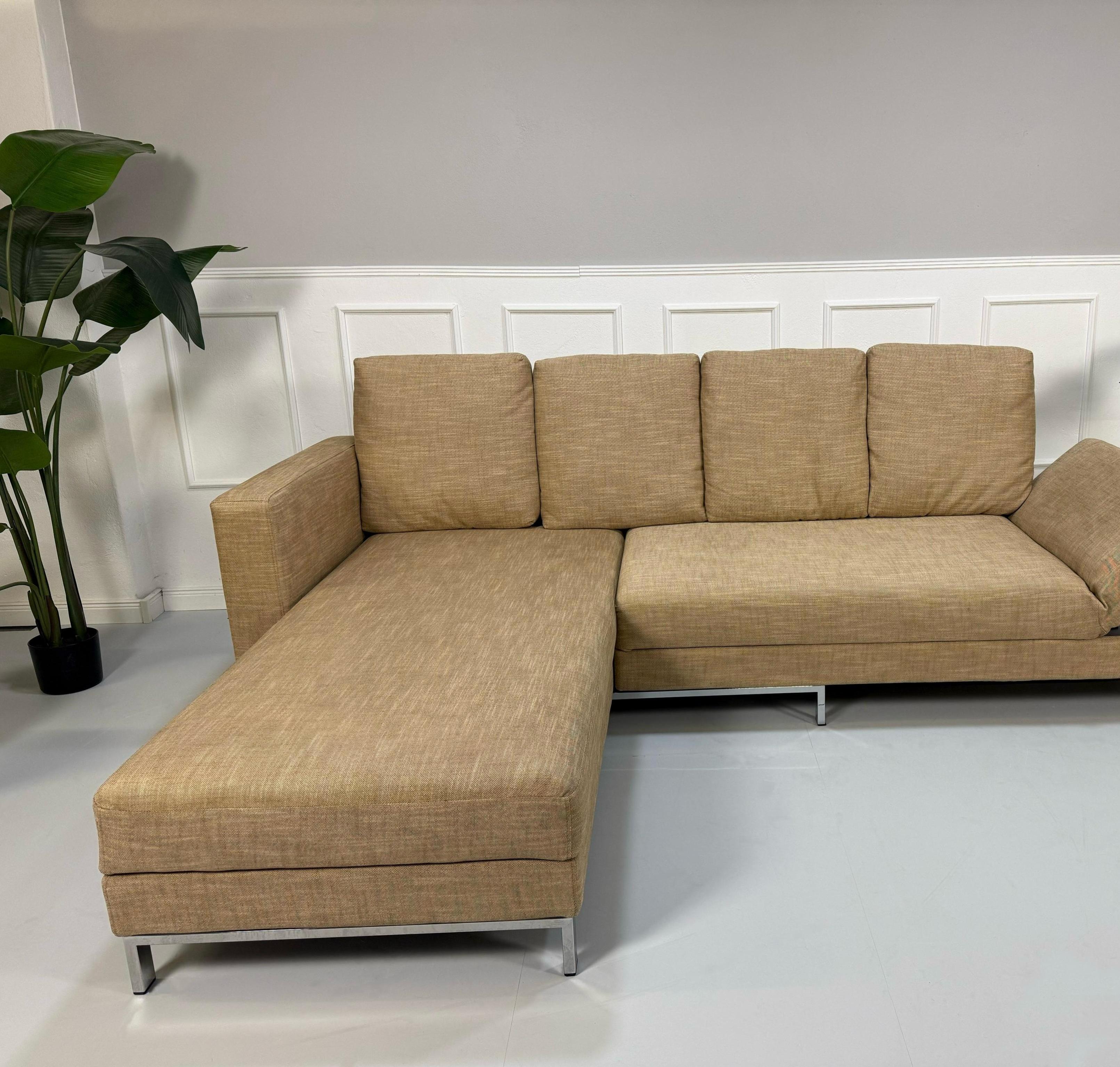 Gebrauchtes beiges Brühl Four Two Designer Stoff Sofa vor einer Wand, stilvoll und modern eingerichtet.