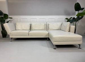 Gebrauchtes weißes Brühl Moule Designer Leder Sofa vor einer Wand, stilvoll und modern eingerichtet.