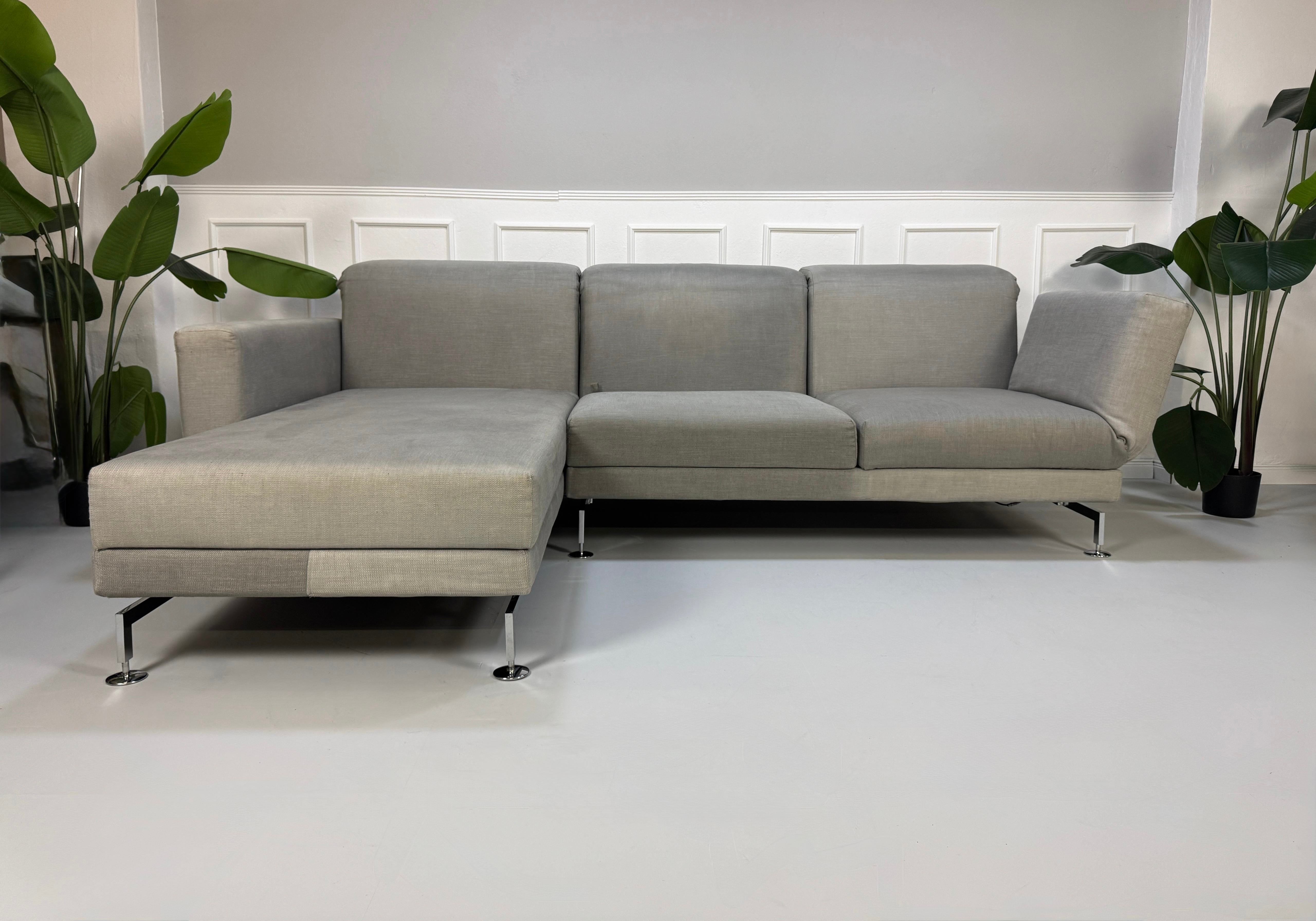 Gebrauchtes graues Brühl Moule Designer Stoff Sofa vor einer Wand, stilvoll und modern eingerichtet.