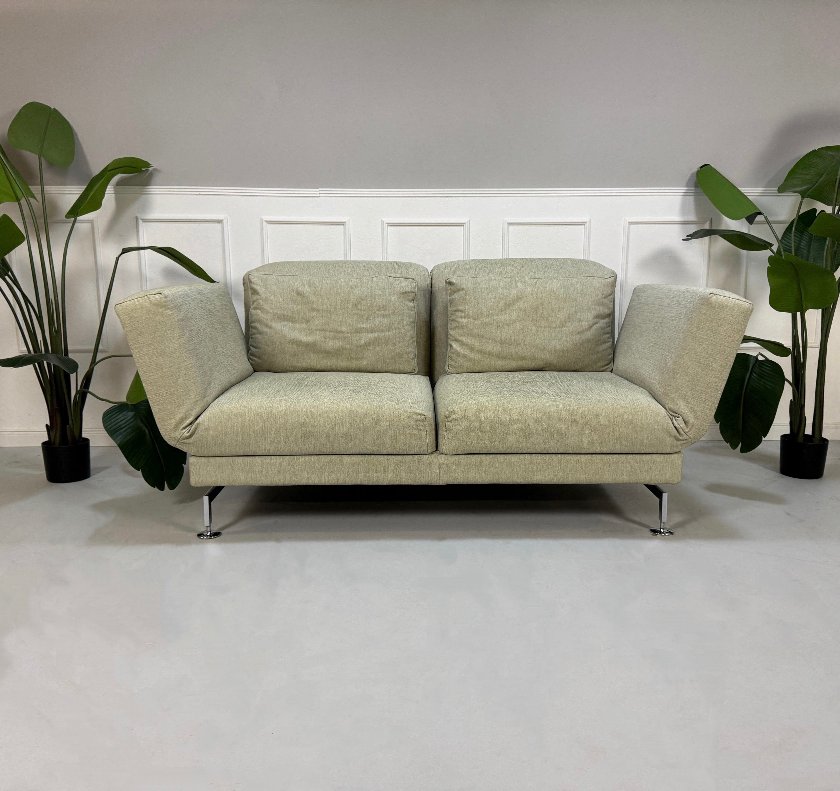 Gebrauchtes beiges Brühl Moule Designer Stoff Sofa vor einer Wand, stilvoll und modern eingerichtet.