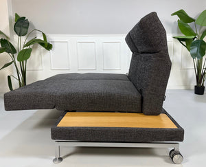 Ausstellungsstück Brühl Moule Designer Stoff Sofa in Grau vor einer Wand, stilvoll und modern eingerichtet.