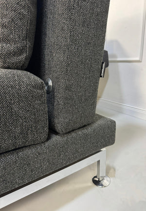 Erneuertes graues Brühl Moule Designer Stoff Sofa vor einer Wand, stilvoll und modern eingerichtet.