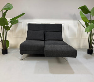 Erneuertes graues Brühl Moule Designer Stoff Sofa vor einer Wand, stilvoll und modern eingerichtet.