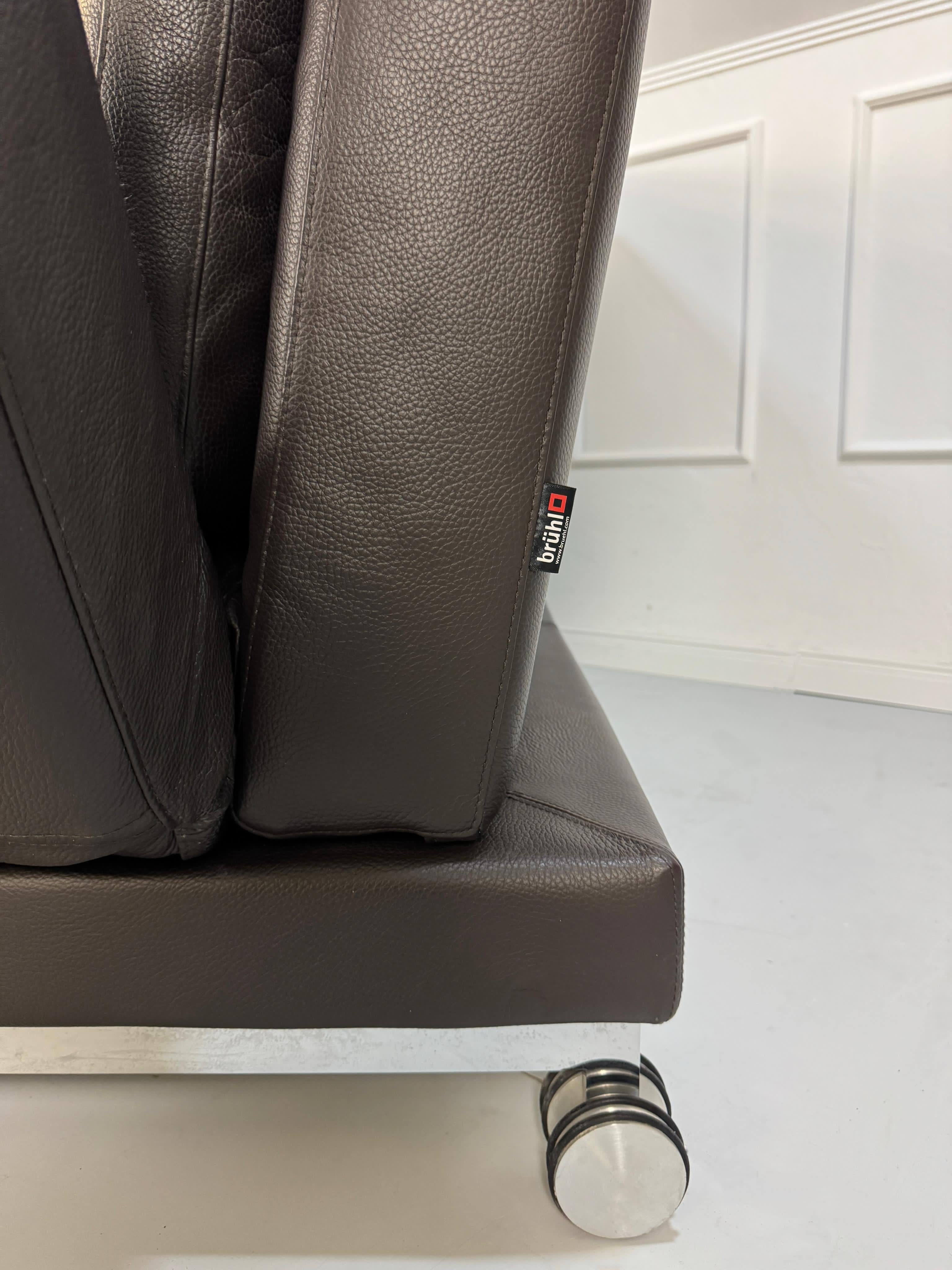 Gebrauchtes braunes Brühl Moule Designer Leder Sofa mit Schlaffunktion vor einer Wand, stilvoll und modern eingerichtet.