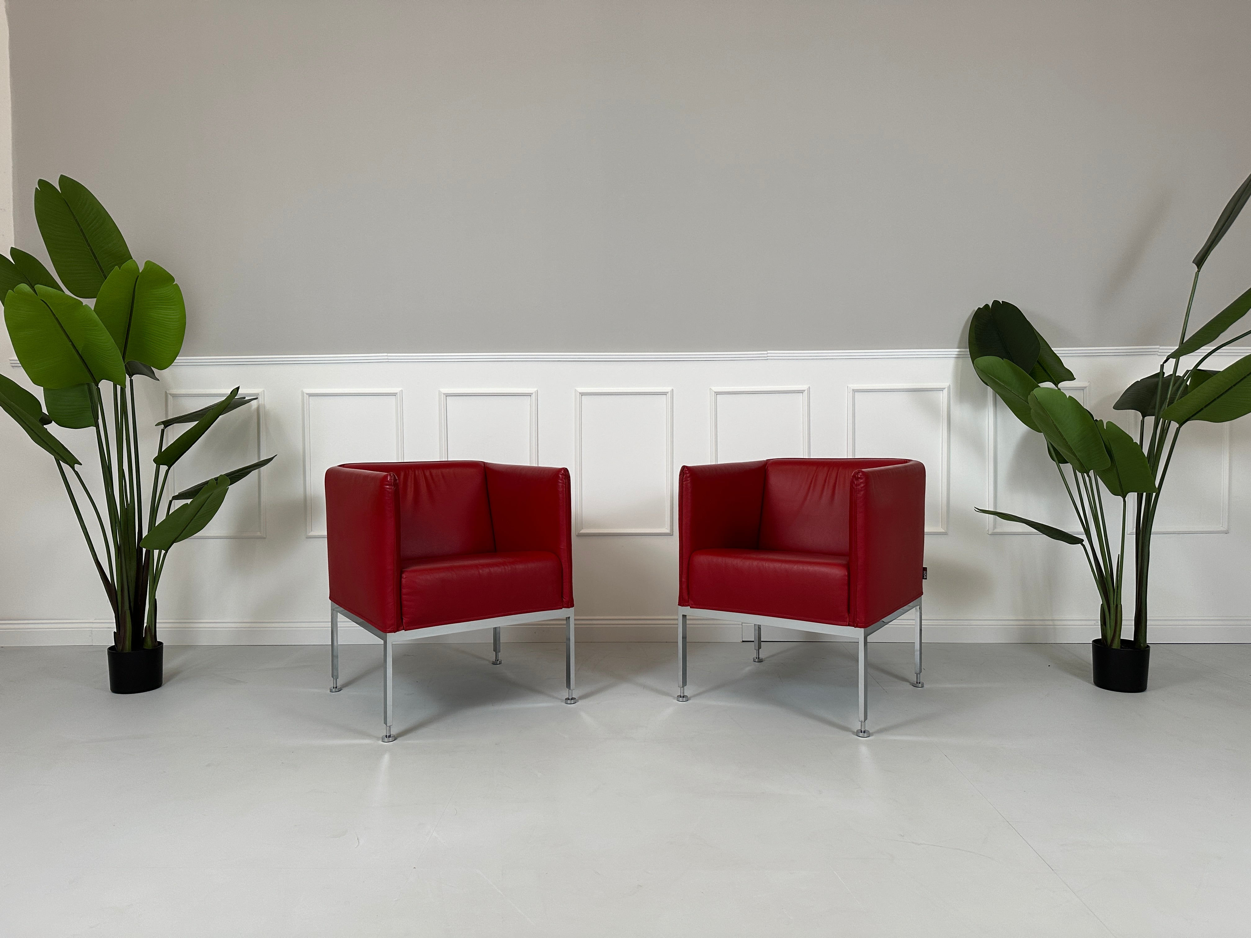 Gebrauchter roter Brühl Randolph Designer Leder Sessel vor einer Wand, stilvoll und modern eingerichtet.