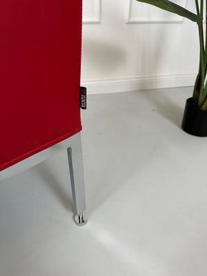 Gebrauchter roter Brühl Randolph Designer Leder Sessel vor einer Wand, stilvoll und modern eingerichtet.